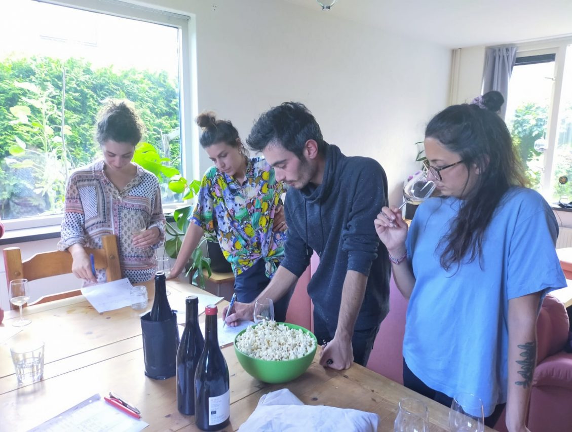 A group of friend is tasting natural wines. They have fun during the event. They are using all there senses to fill in the evaluation grid with flavour and aroma characteristics